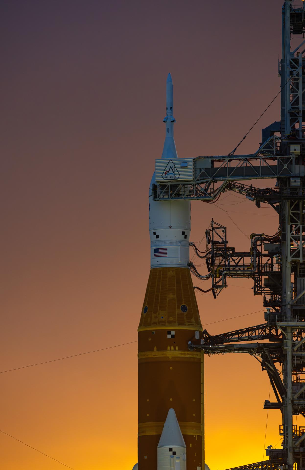 This image shows a sunset of NASA’s SLS (Space Launch System) and Orion spacecraft at NASA’s Kennedy Space Center. NASA's massive Crawler-Transporter, upgraded for the Artemis program, carried the powerful SLS rocket and Orion spacecraft on the Mobile Launcher from the Vehicle Assembly Building to Launch Pad 39B at Kennedy Space Center in preparation for the Artemis II mission.